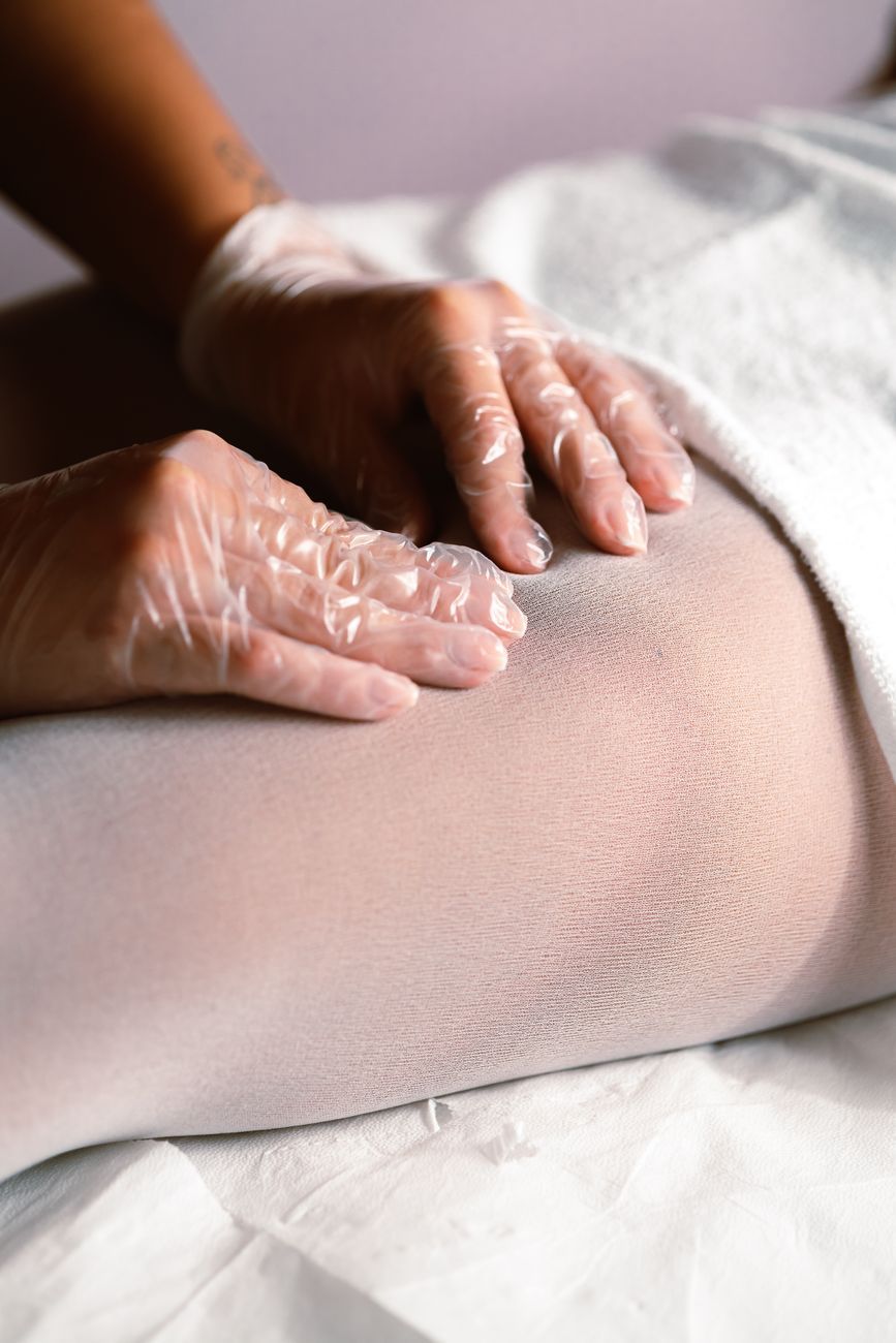 Imagen ilustrativa: manos con guantes de una terapeuta sobre la pierna de un paciente